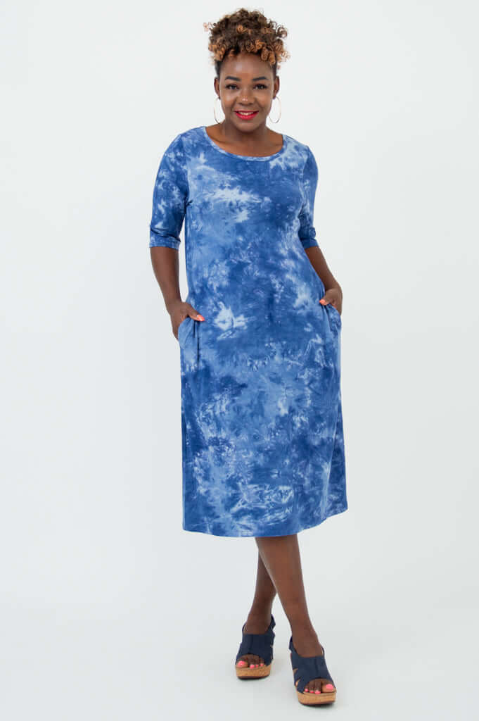 Woman wearing a blue tie dye dress with elbow sleeves and pockets, front view