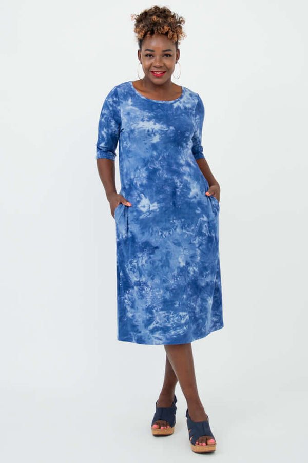 Woman wearing a blue tie dye dress with elbow sleeves and pockets, front view