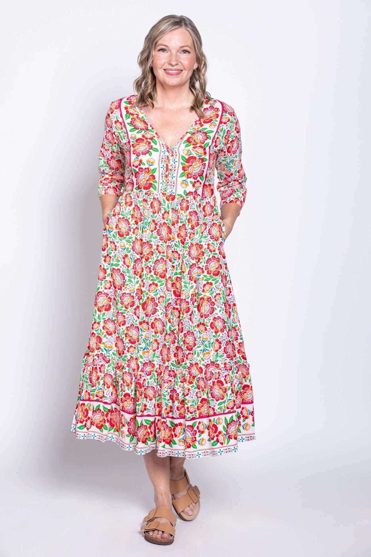Model with hands in pockets showcasing front and side of vibrant floral midi dress
