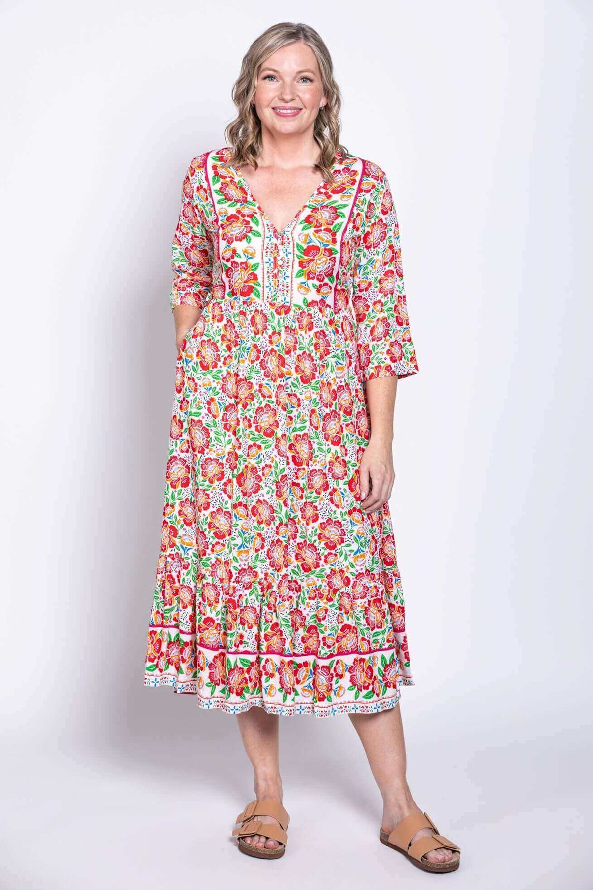 Model wearing floral batik dress with pockets, smiling and facing forward