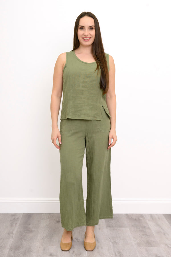 Woman wearing a green sleeveless top, wide-leg pants against, and tan shoes against a white background, front view