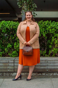Model outdoors in Parisian Chanel Cardigan over an orange dress, holding a brown handbag