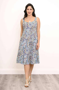Woman standing in a paisley A-line dress, facing forward with hands at sides