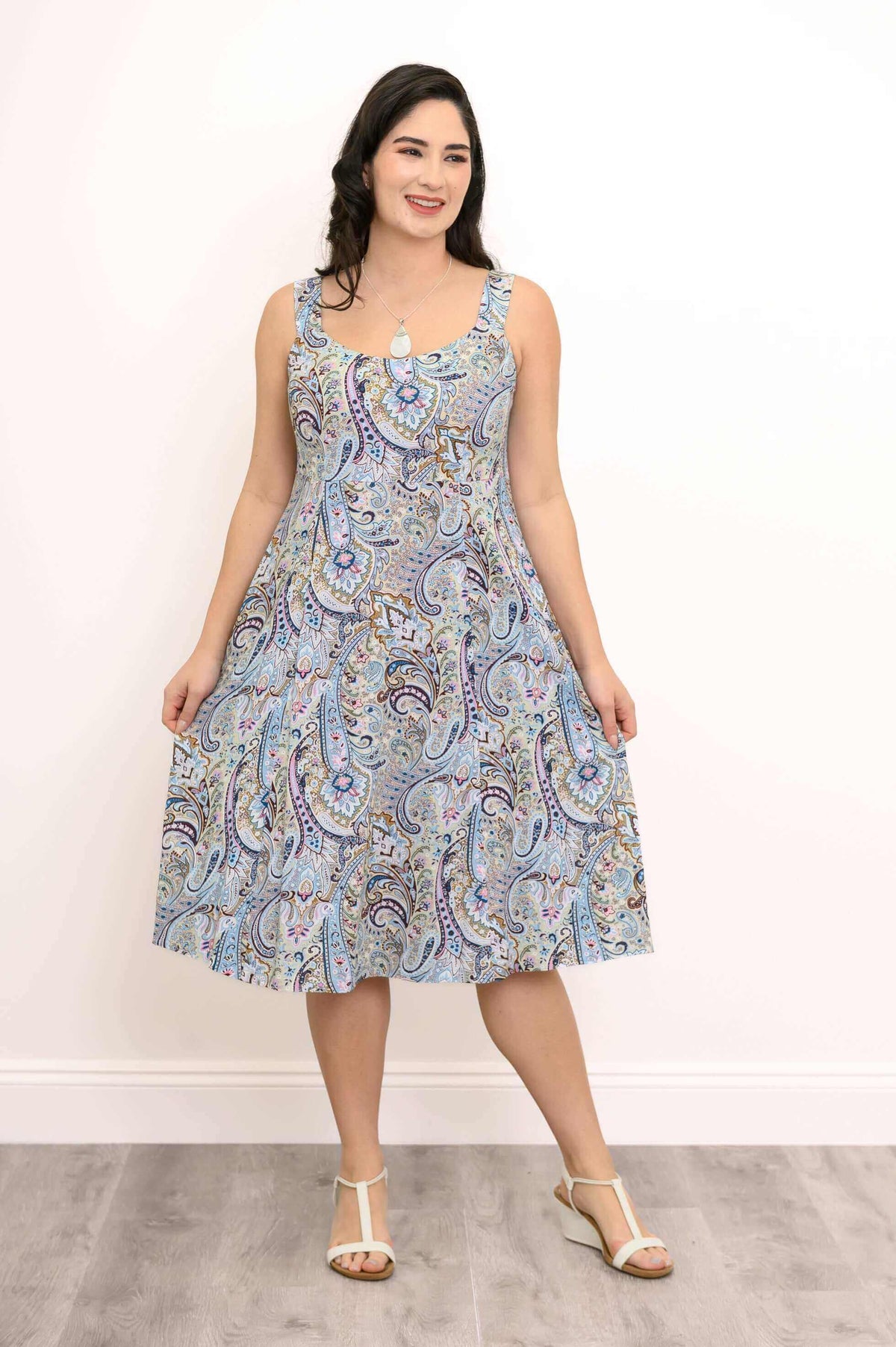 Woman in a paisley sleeveless dress holding out skirt, smiling