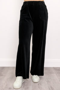 Woman wearing black wide-leg corduroy pants and white shoes on a white background, front view