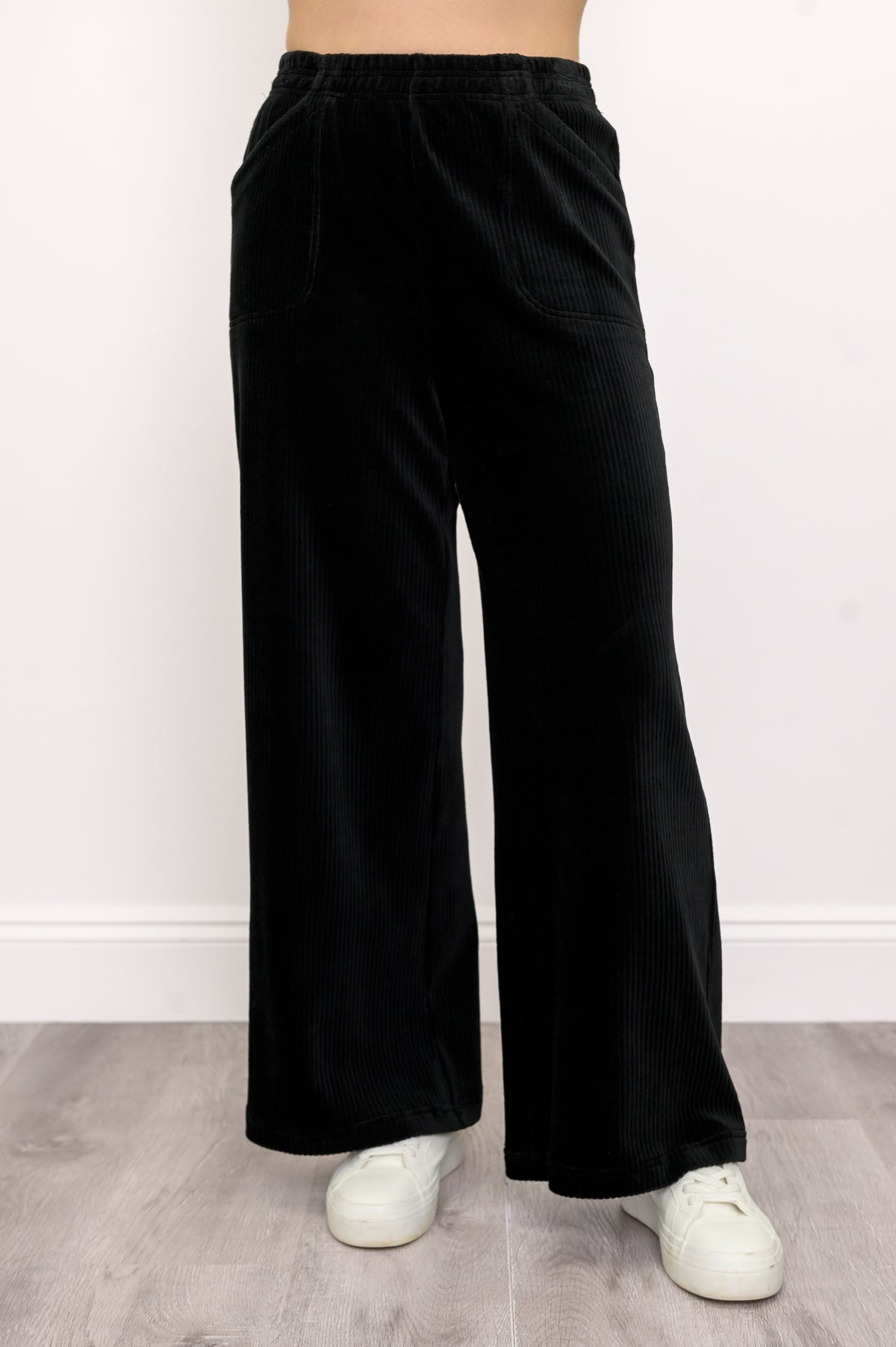 Woman wearing black wide-leg cotton corduroy trousers with white sneakers