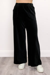 Woman wearing black wide-leg cotton corduroy trousers with white sneakers