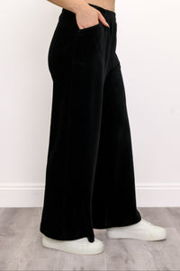 Side view of black wide-leg corduroy trousers with front pockets and an elastic waist