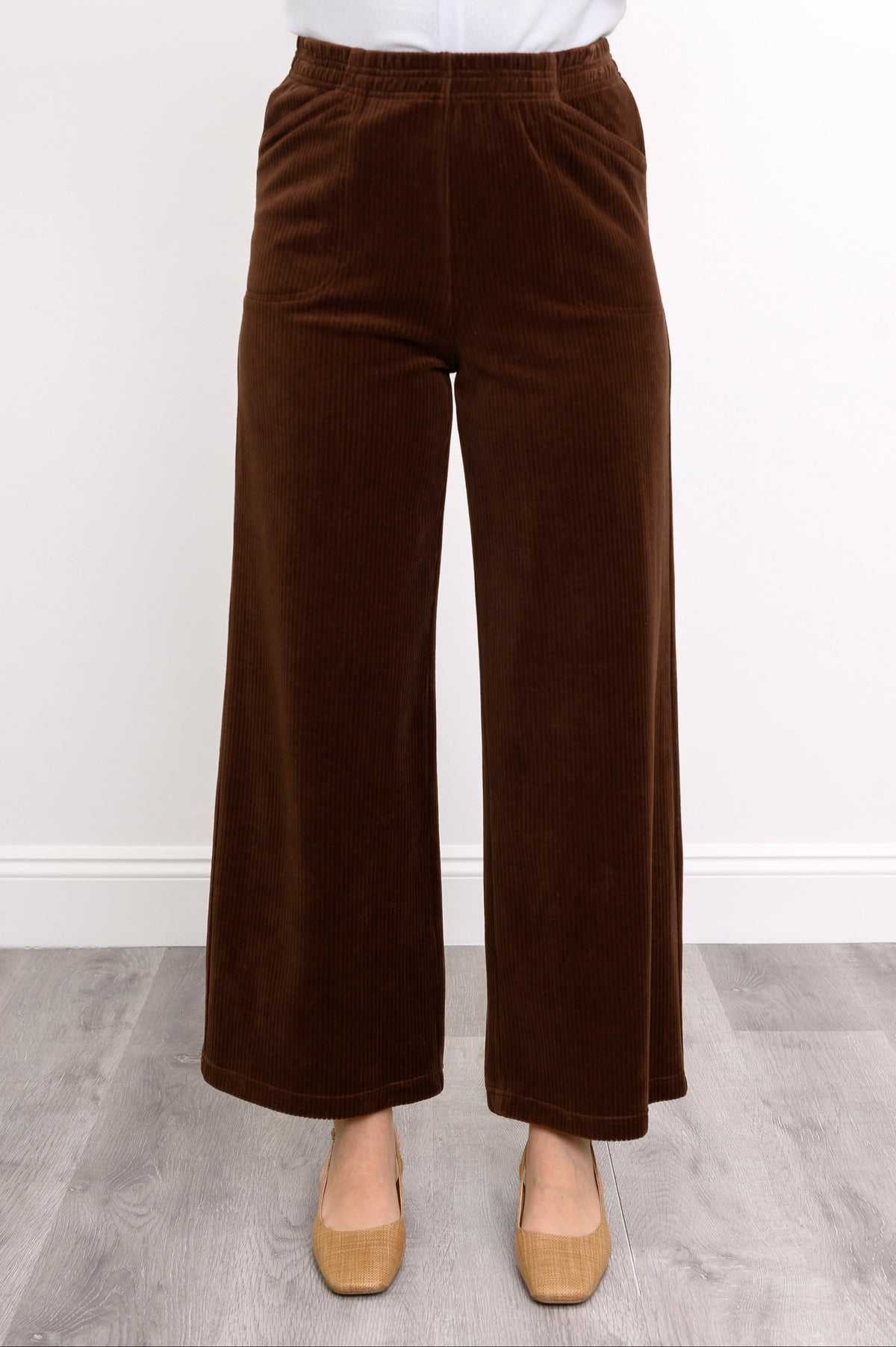 Close-up front view of woman wearing wide-leg chocolate colored pants in corduroy fabric