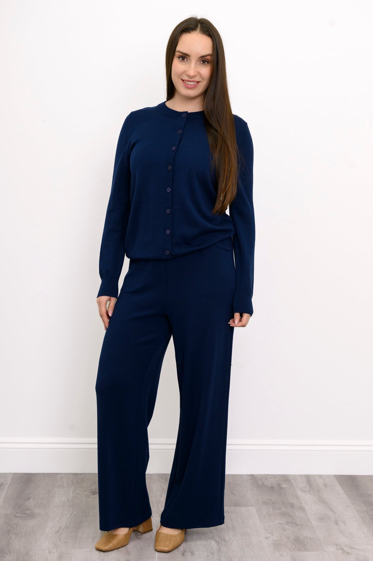 Woman wearing a navy blue knit top and navy blue knit pants on a white background, front view