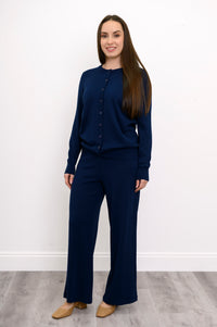 Woman modeling a classic navy blue buttoned knit cardigan sweater with ribbed trim details on white.