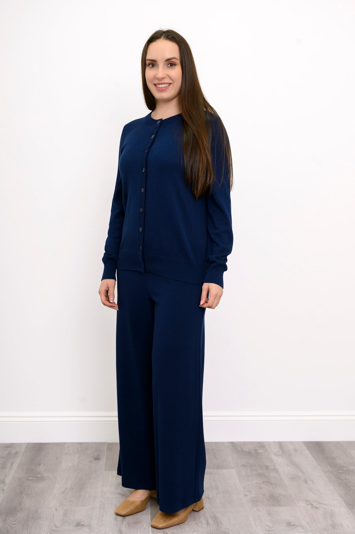 Front view of a woman wearing a navy crewneck button up cardigan styled in a monochromatic outfit.