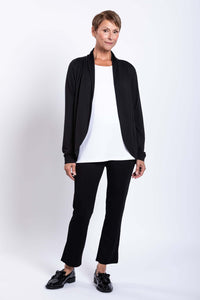 Woman in black French Terry jacket, white top, and black pants, partial side view