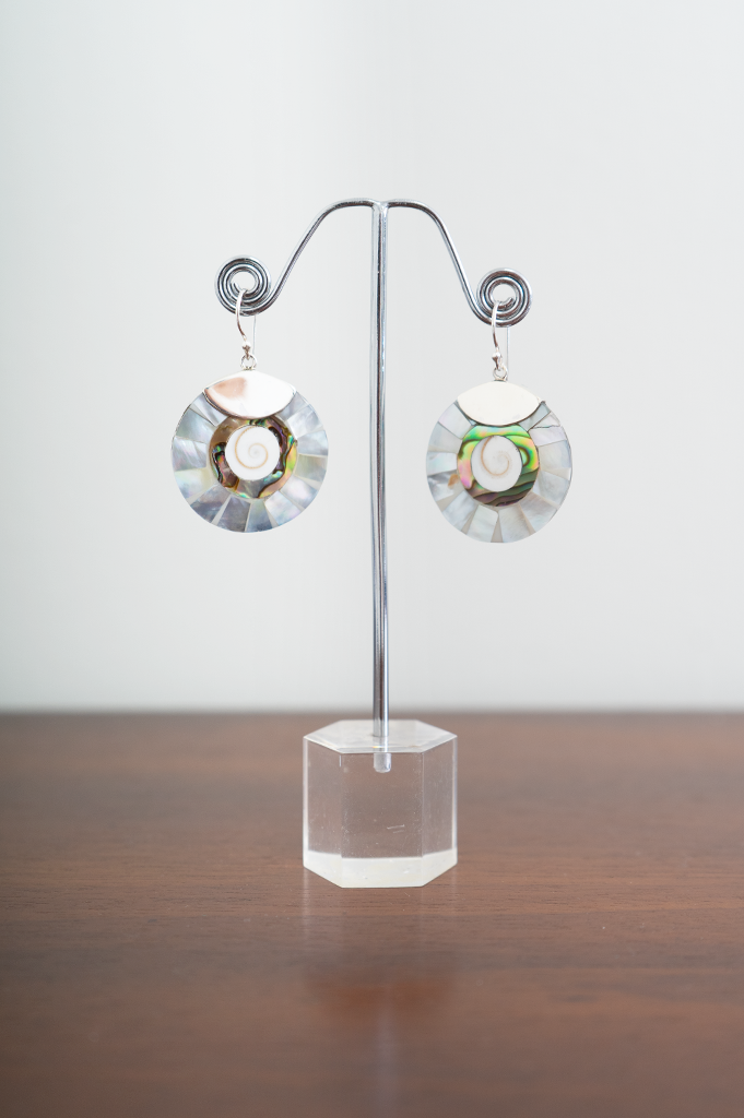 A pair of sterling silver earrings with mixed shell pendants displayed on a metal stand