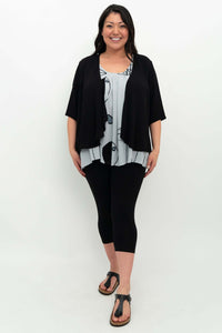 Model layering black cardigan over light blue pleated tank top with fish print and black leggings