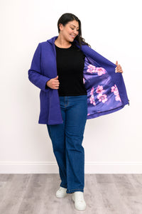 Woman showing off the satin violet and lilac floral lining of her bright purple zip-up jacket