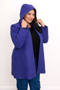 Woman wearing a violet purple jacket unzipped and with the hood over her head