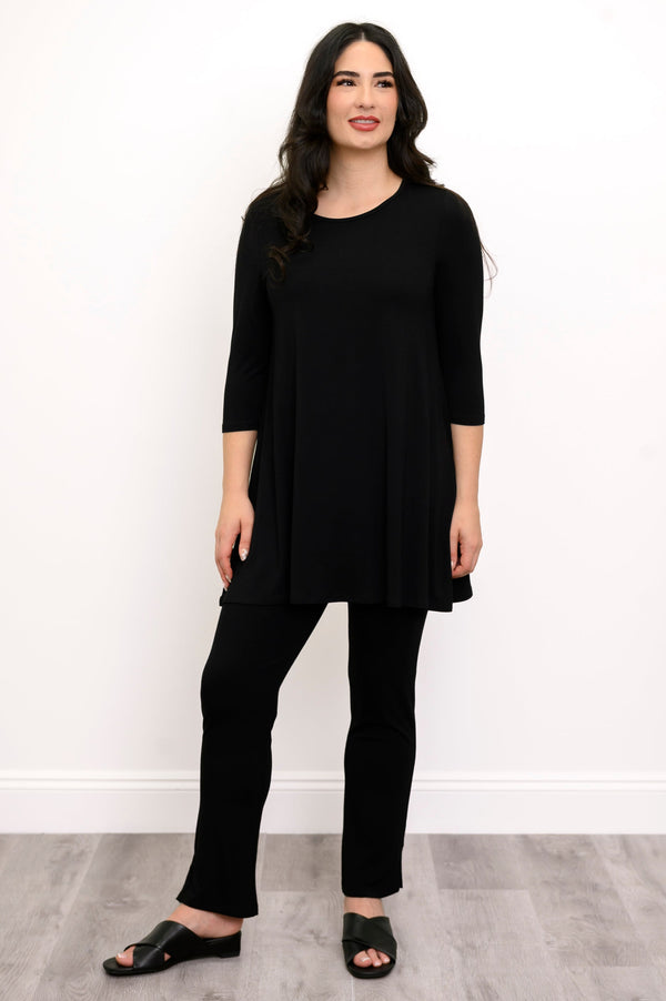 Full body front view of woman modelling a black round neck tunic, black slim fit pants, and black shoes