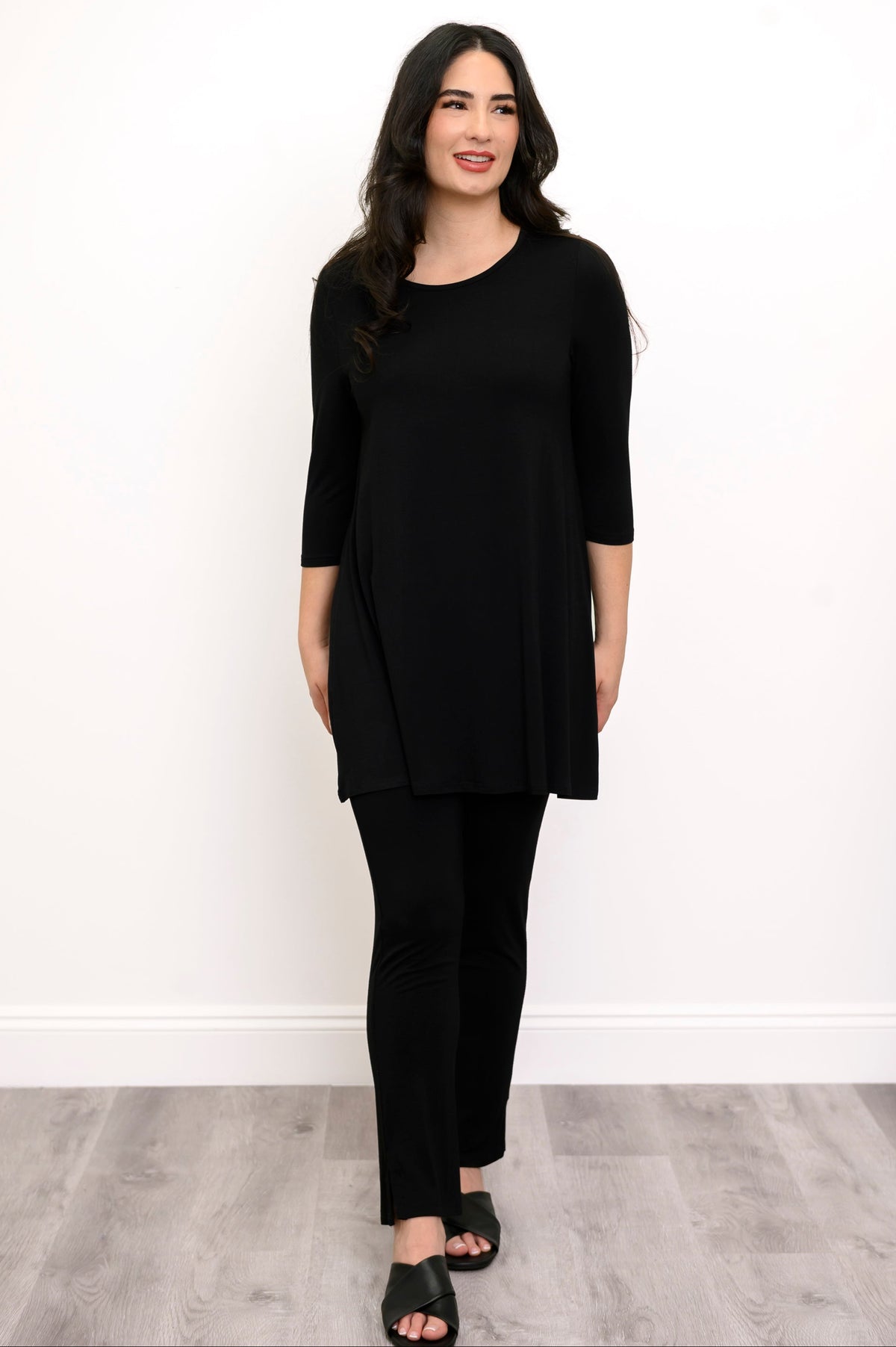 Woman wearing a black tunic, black pants, and back sandals