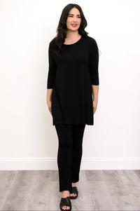 Woman wearing a black tunic, black pants, and back sandals