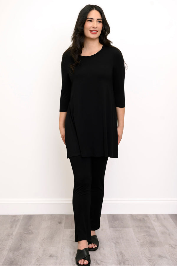 Woman wearing a black tunic, black pants, and back sandals