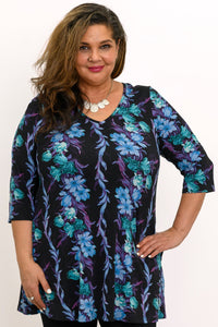 Smiling woman wearing a blue and teal floral print A-line tunic with 3/4 sleeves, front view.