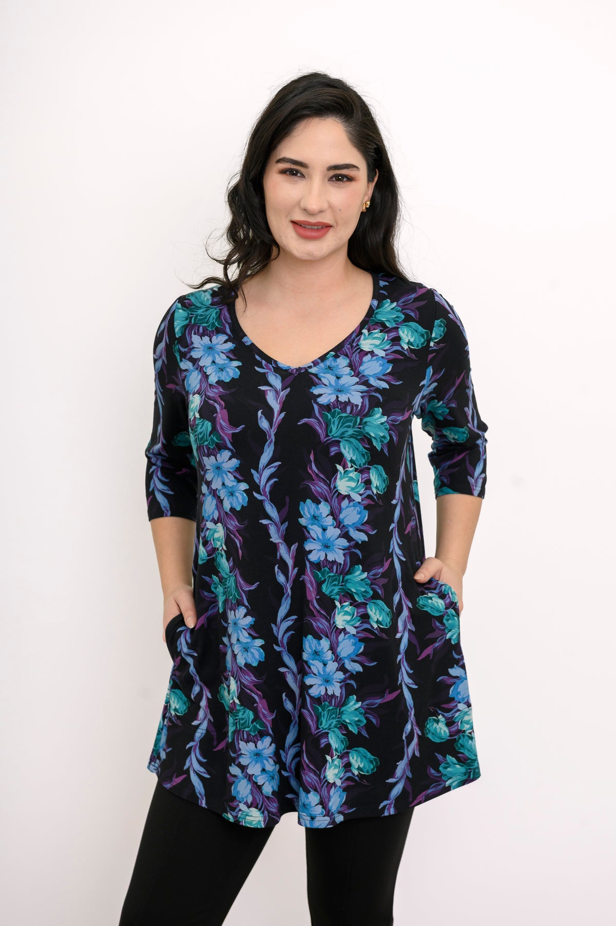 Model posing in a flowy blue-teal floral print bamboo tunic showing the flattering hip-covering length.