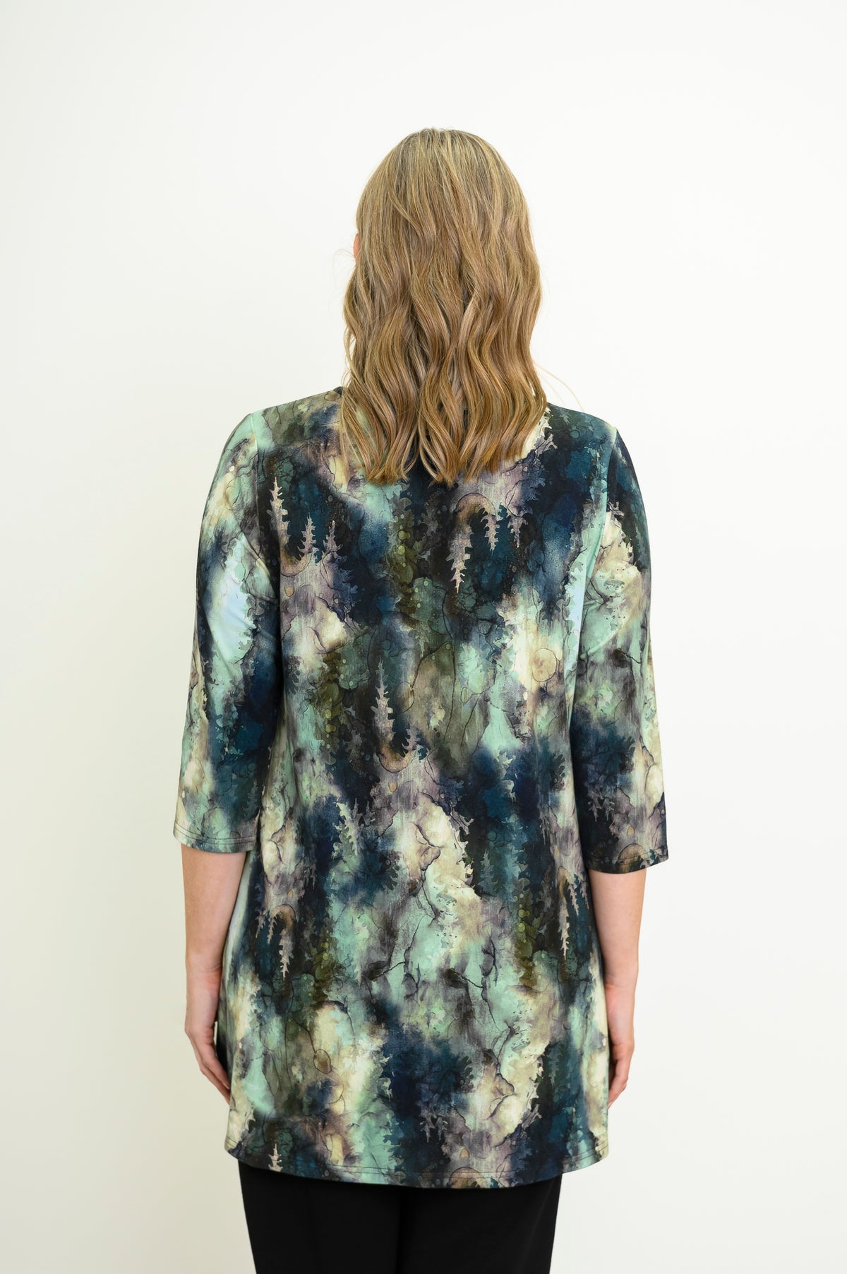 Rear view of a patterned long-sleeve knit top on a model, highlighting the flattering hip-covering length.