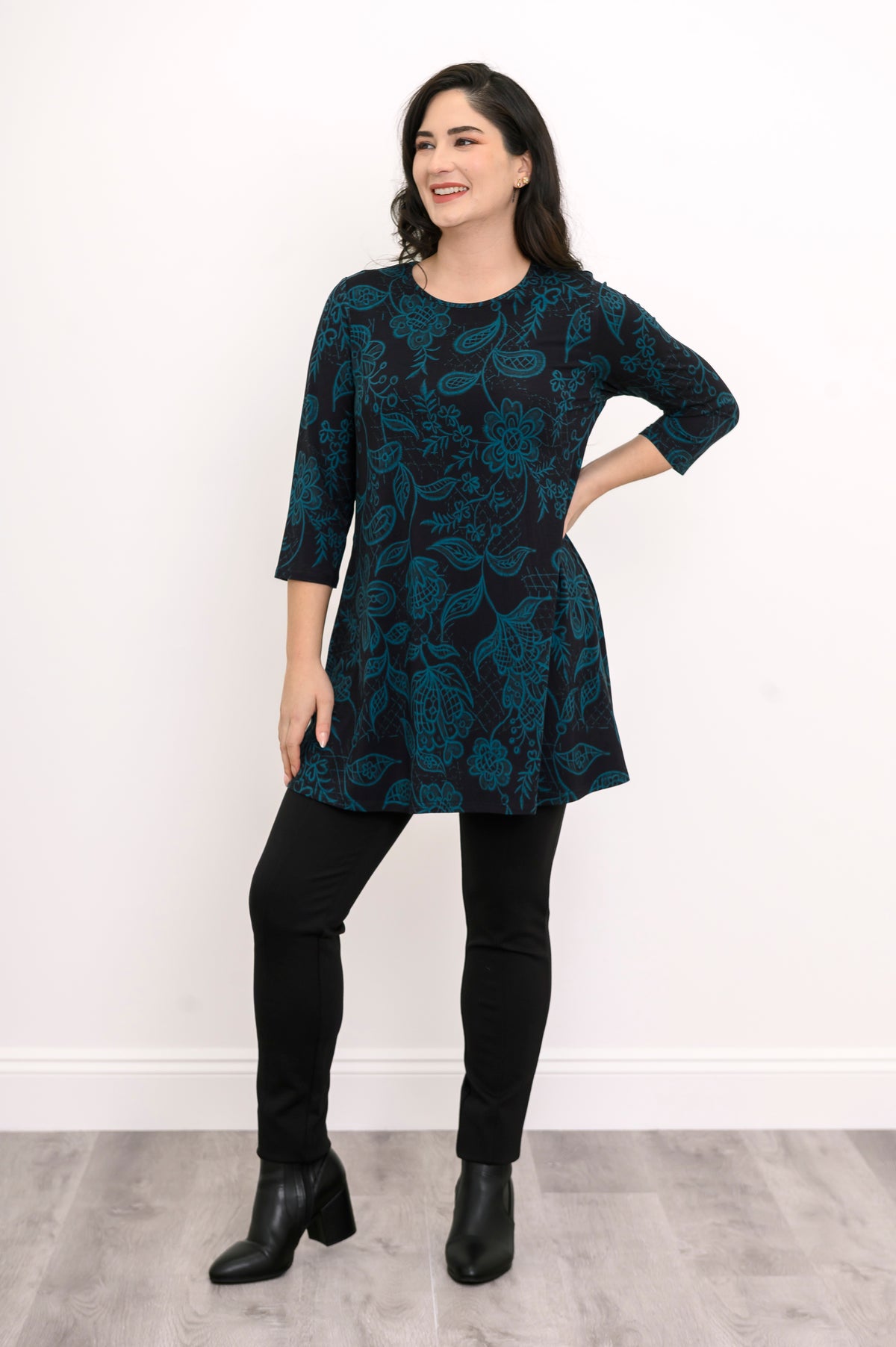 Women's dark teal botanical print knit blouse with comfortable 3/4 sleeves, styled with black pants.