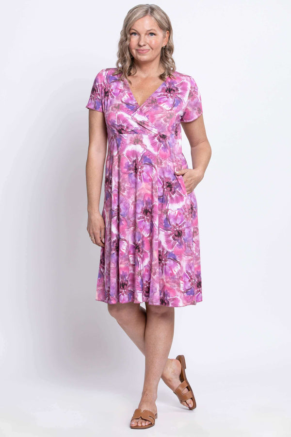 Woman wearing a pink and purple floral bamboo crossover dress, hand in pocket