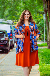 Plus-size model outside, layering Van Gogh art tunic over orange dress