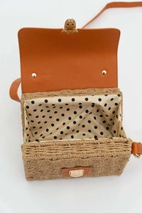 Open crossbody bag showing polka dot fabric lining and rattan construction
