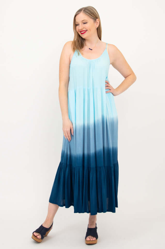 Woman posing with hand on hip in a blue gradient maxi dress with scoop neckline