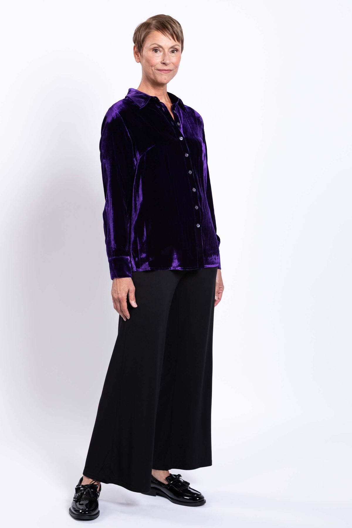 Woman in purple silk velvet blouse standing at an angle