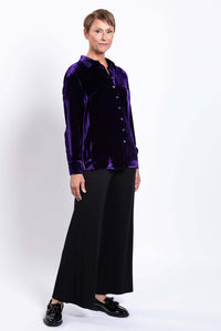 Woman in purple silk velvet blouse standing at an angle