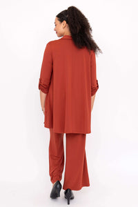 Rear angle of woman in rust pants and matching shirt, styled with black heels