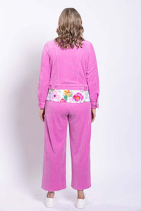 Rear view of woman in pink corduroy jacket and matching pants, floral blouse visible