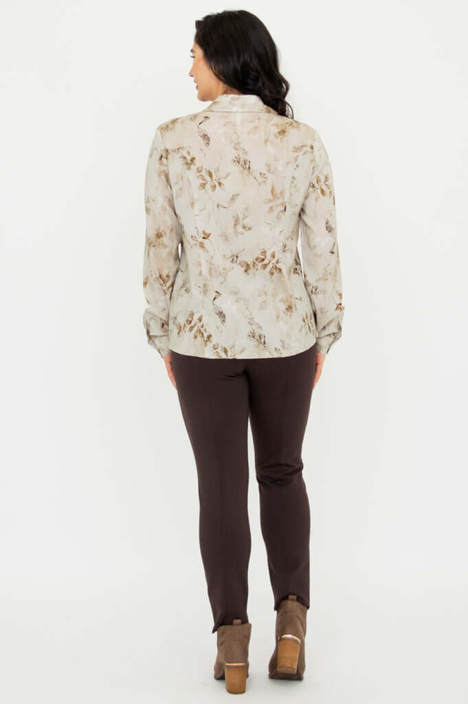 Back view of woman wearing beige floral blouse with brown pants