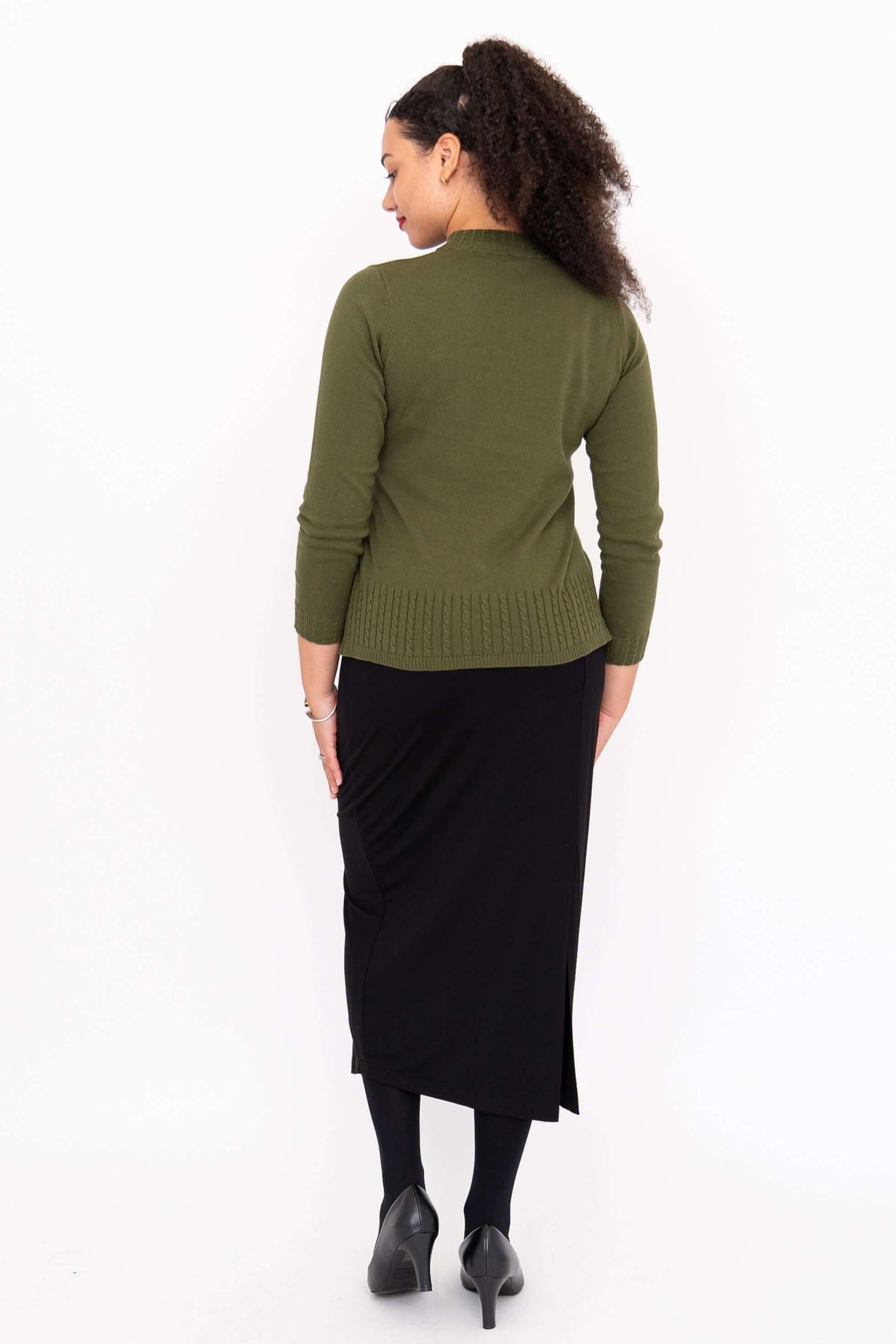 Back view of woman in olive green sweater and black skirt, arms at sides