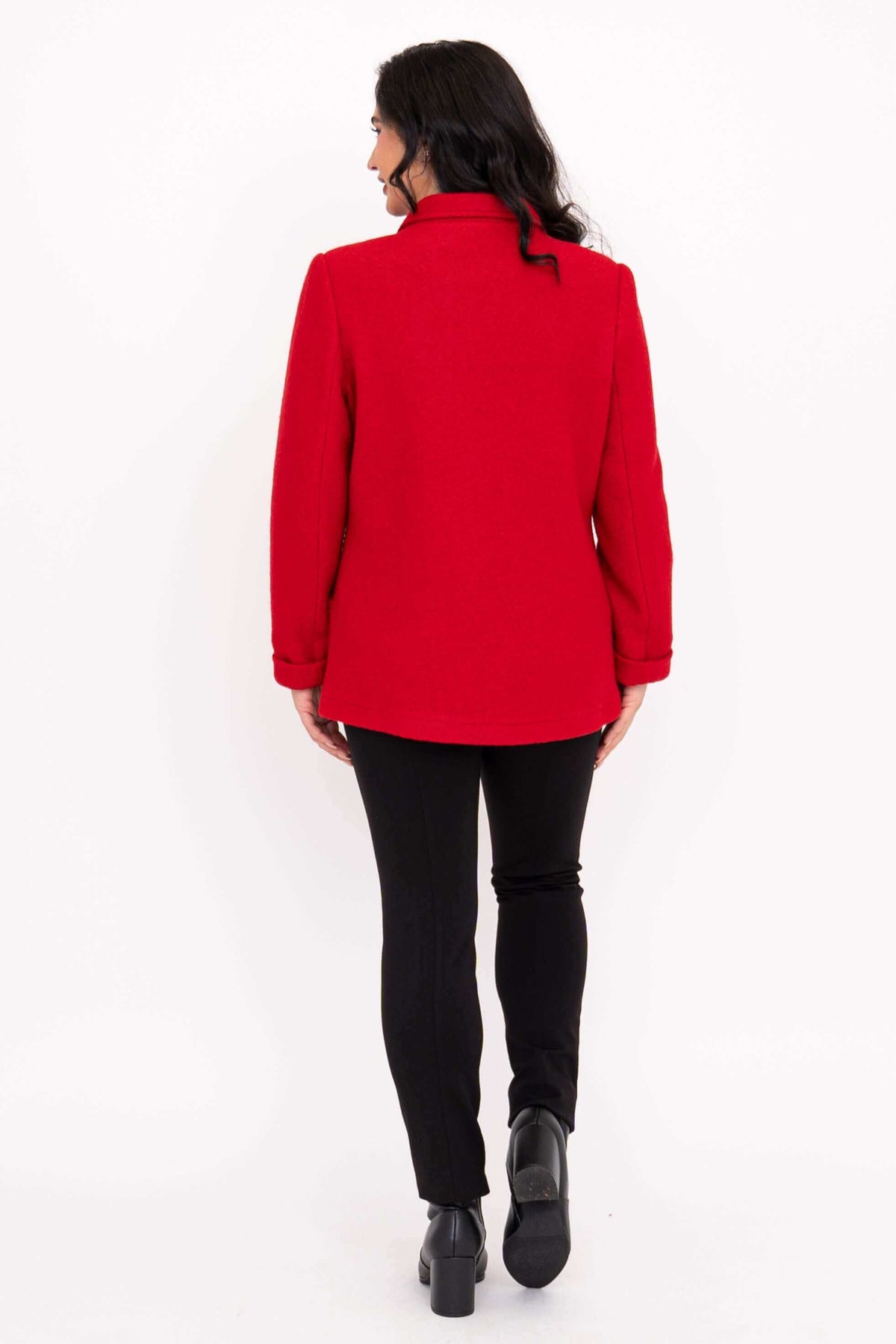 Back view of a woman wearing a red coat with black pants and heeled boots