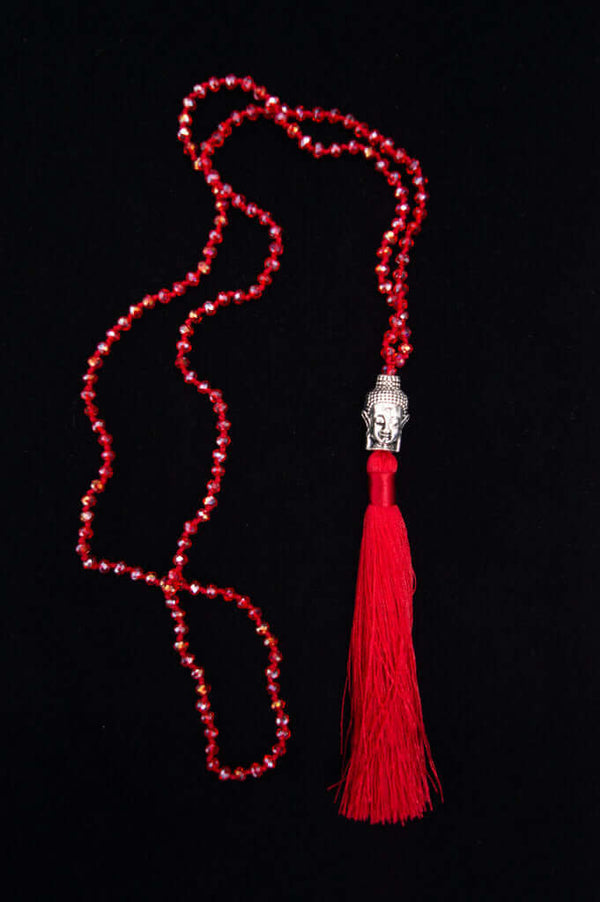 Red beaded mala necklace featuring a Buddha head pendant and a bright red tassel