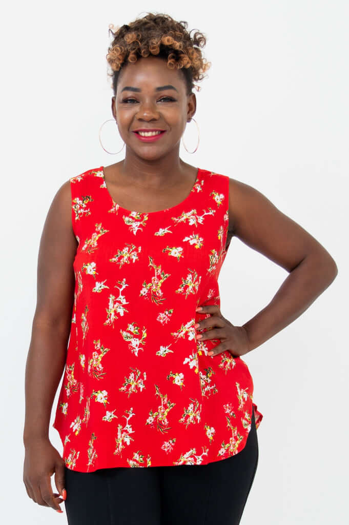 Woman wearing a sleeveless red floral tank top and black pants, front view