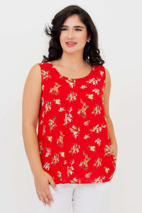 Woman wearing a sleeveless red floral tank top and white pants, front view