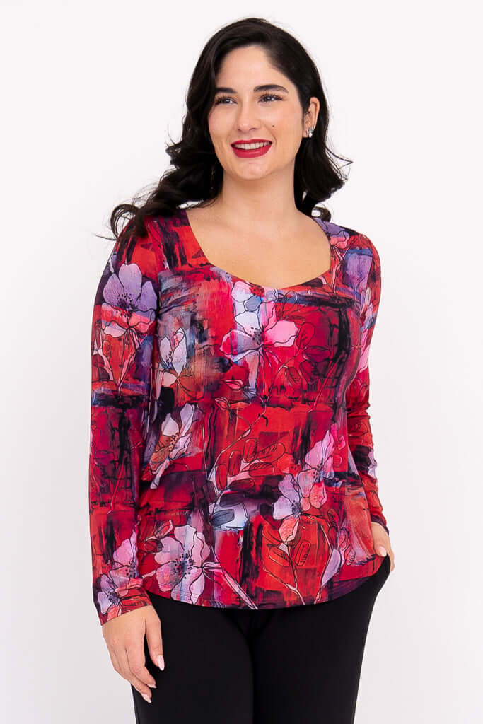 Woman wearing a red floral sweetheart neckline long sleeve top, smiling