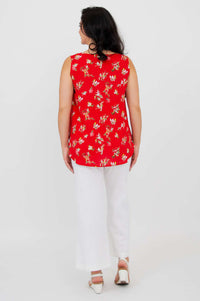 Woman showing back of red floral tank top with white pants