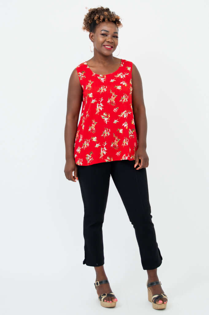 Woman in a red floral tank top and black pants, full body view