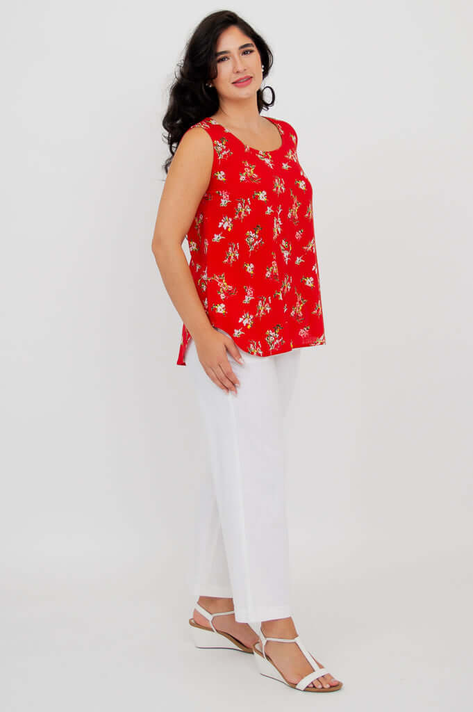 Woman in a red floral tank top and white pants, side angle