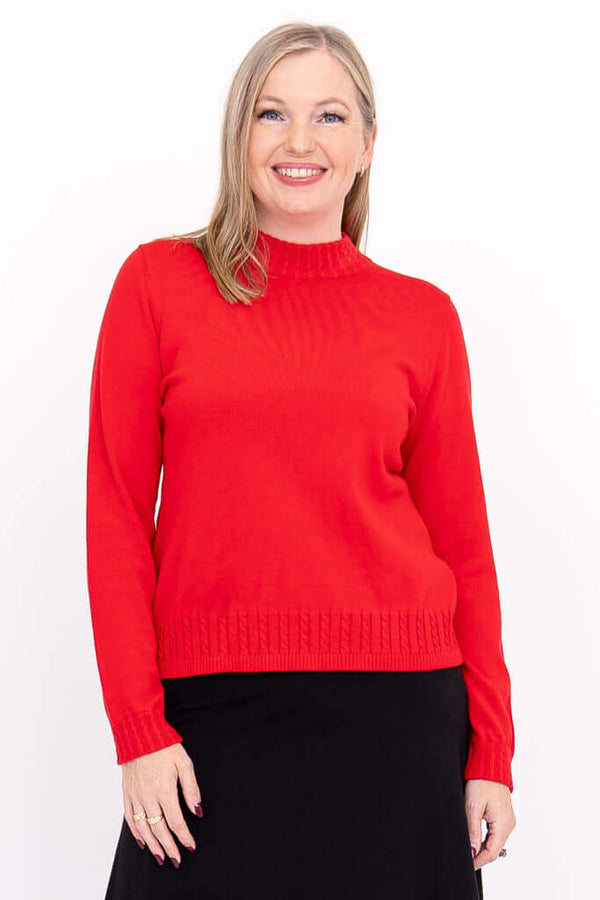 Woman wearing a red mock neck sweater with cable knit detailing and long sleeves