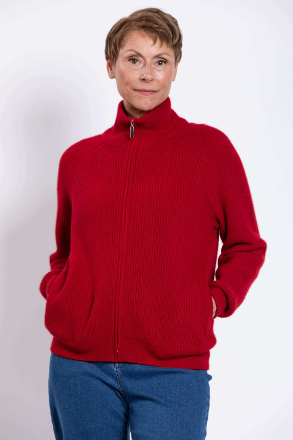 Person wearing a red ribbed zip-up cardigan with a high collar and hands in pockets