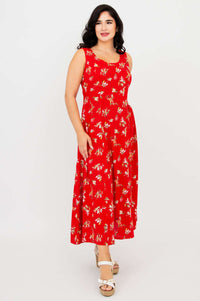 Woman wearing a red sleeveless floral maxi dress with scoop neckline and white heels